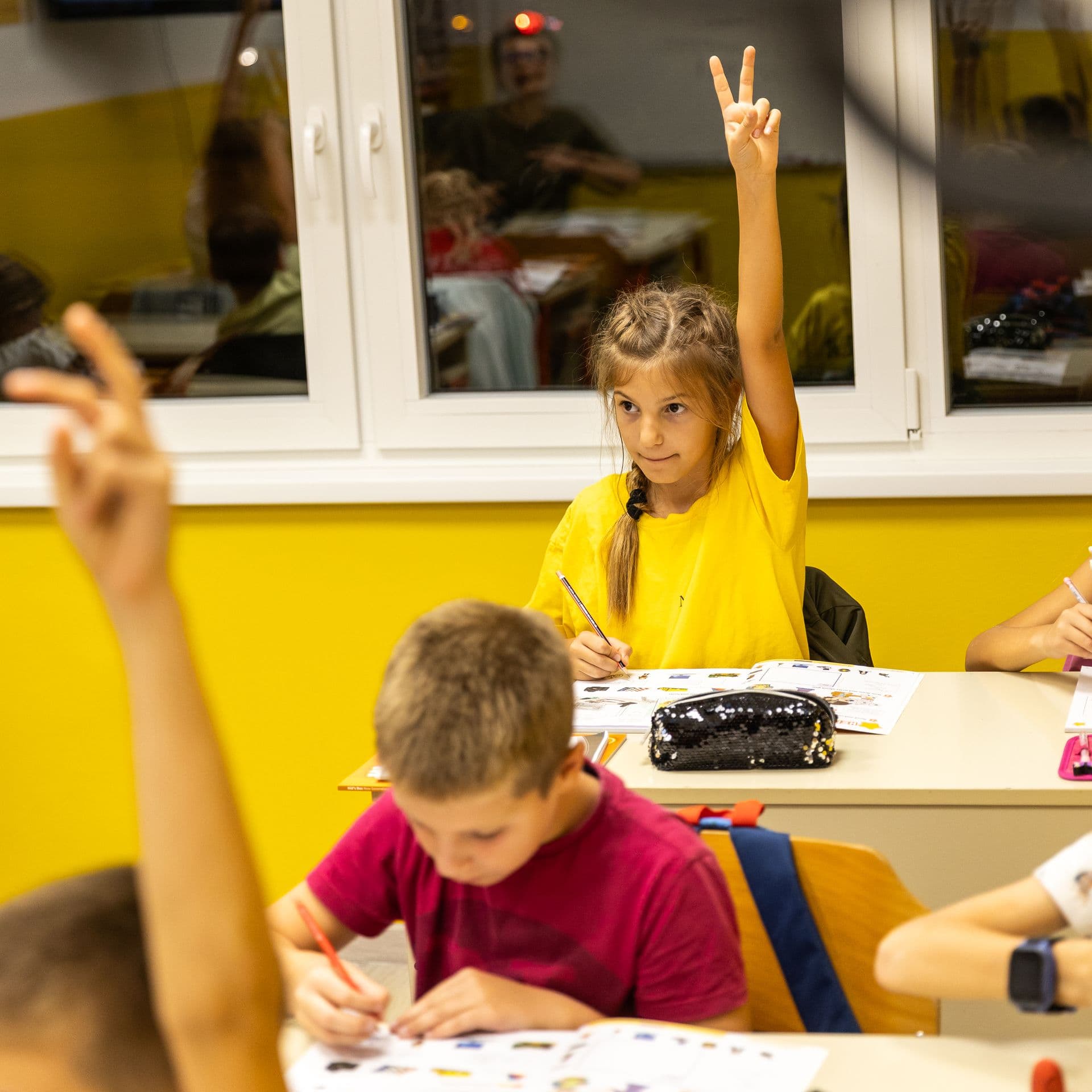 Pupils in a classroom raising their hands