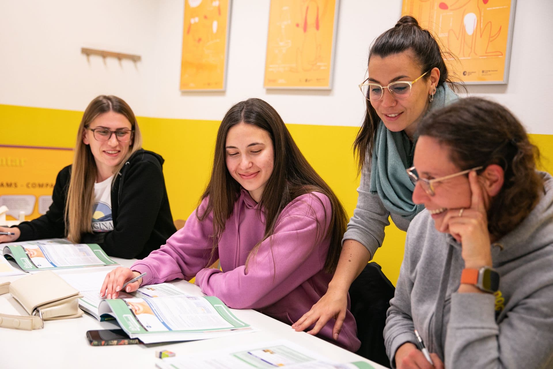 A teacher helping a group of learners with their coursebook