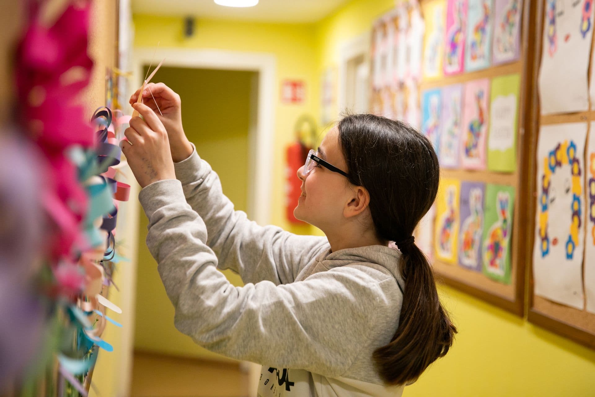 A pupil with glasses pinning her work to a board