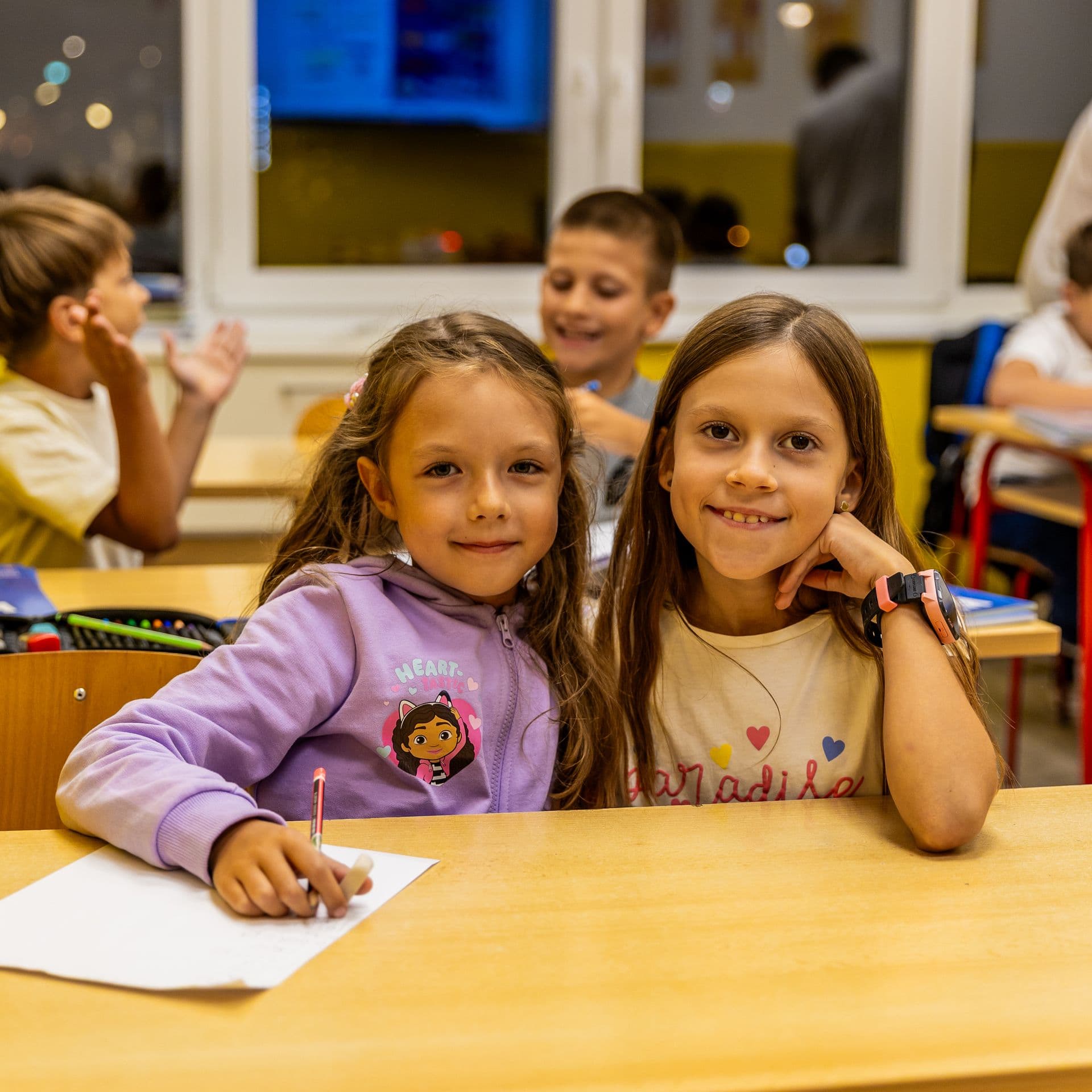 Dvije djevojčice mašu i smiju se u učionici